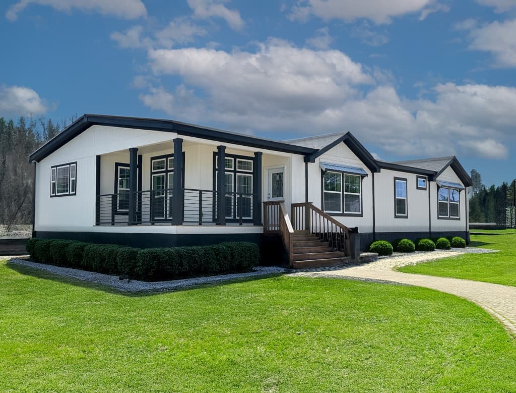 A modern manufactured home with white siding and dark trim on a landscaped lot